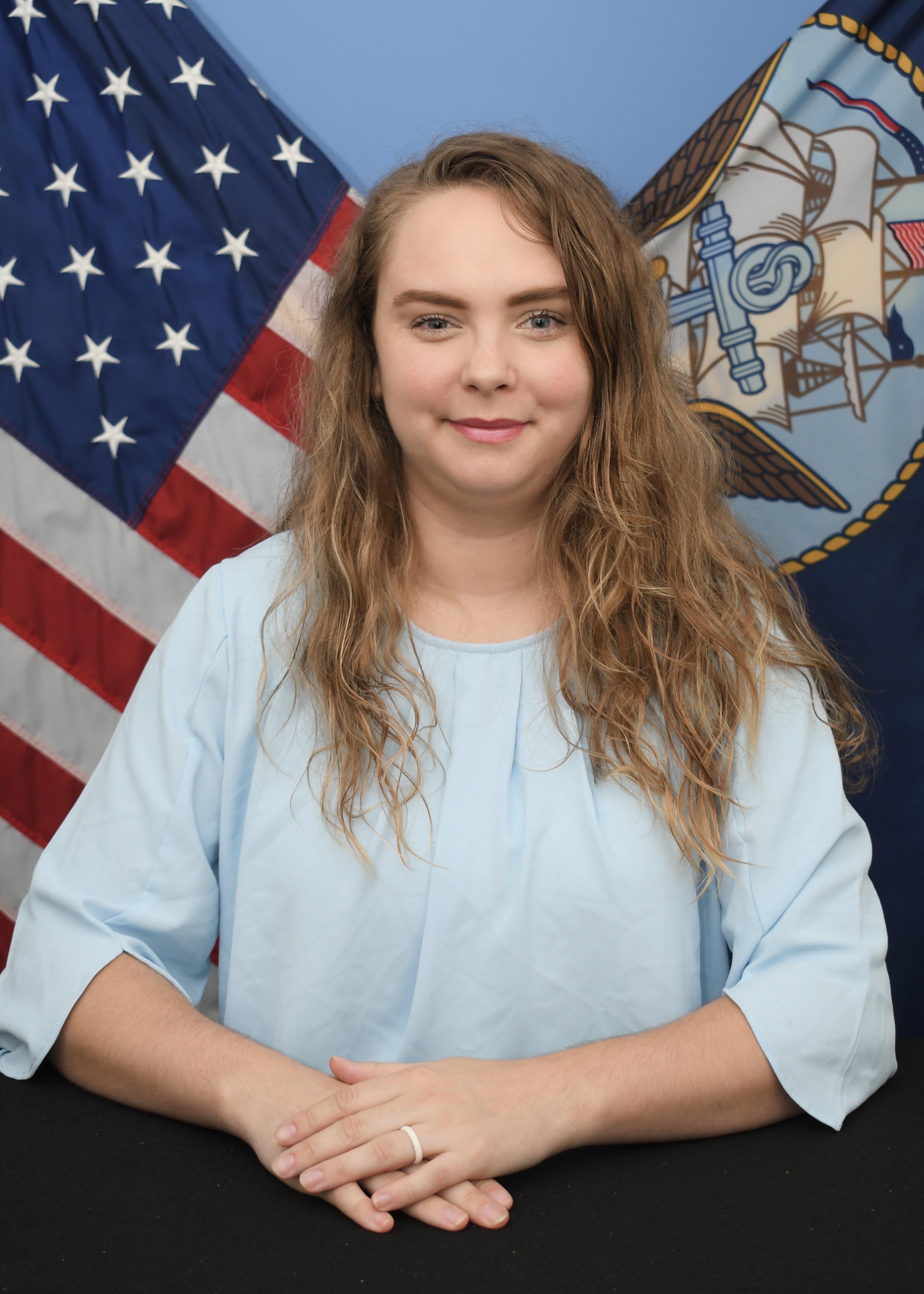 Posed picture of Jamye in front of American flag and Navy flag